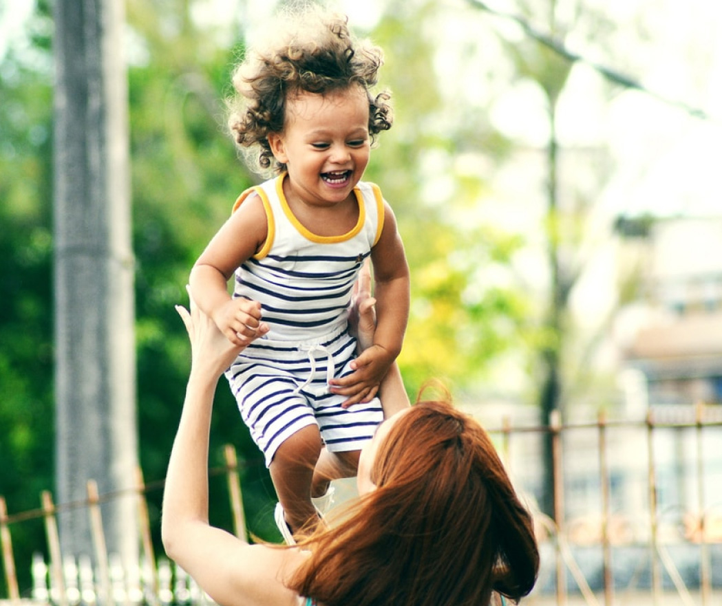 A woman plays with a laughing toddler.