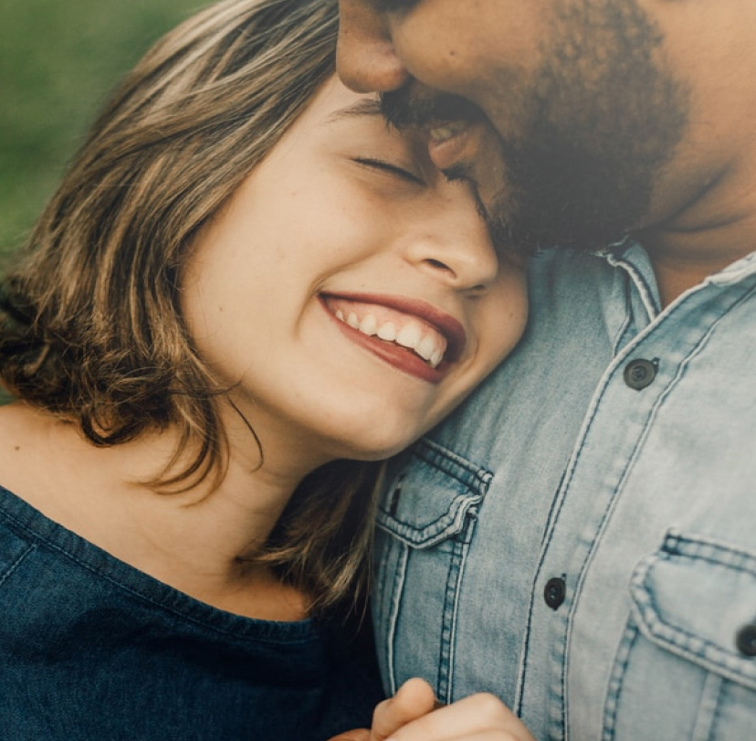 A couple shares a happy moment, smiling and hugging closely.