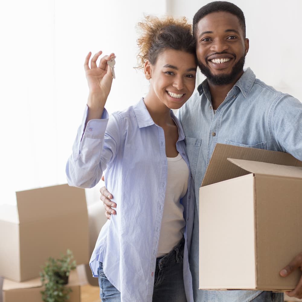 A Happy couple in the middle of moving in, smile at the camera