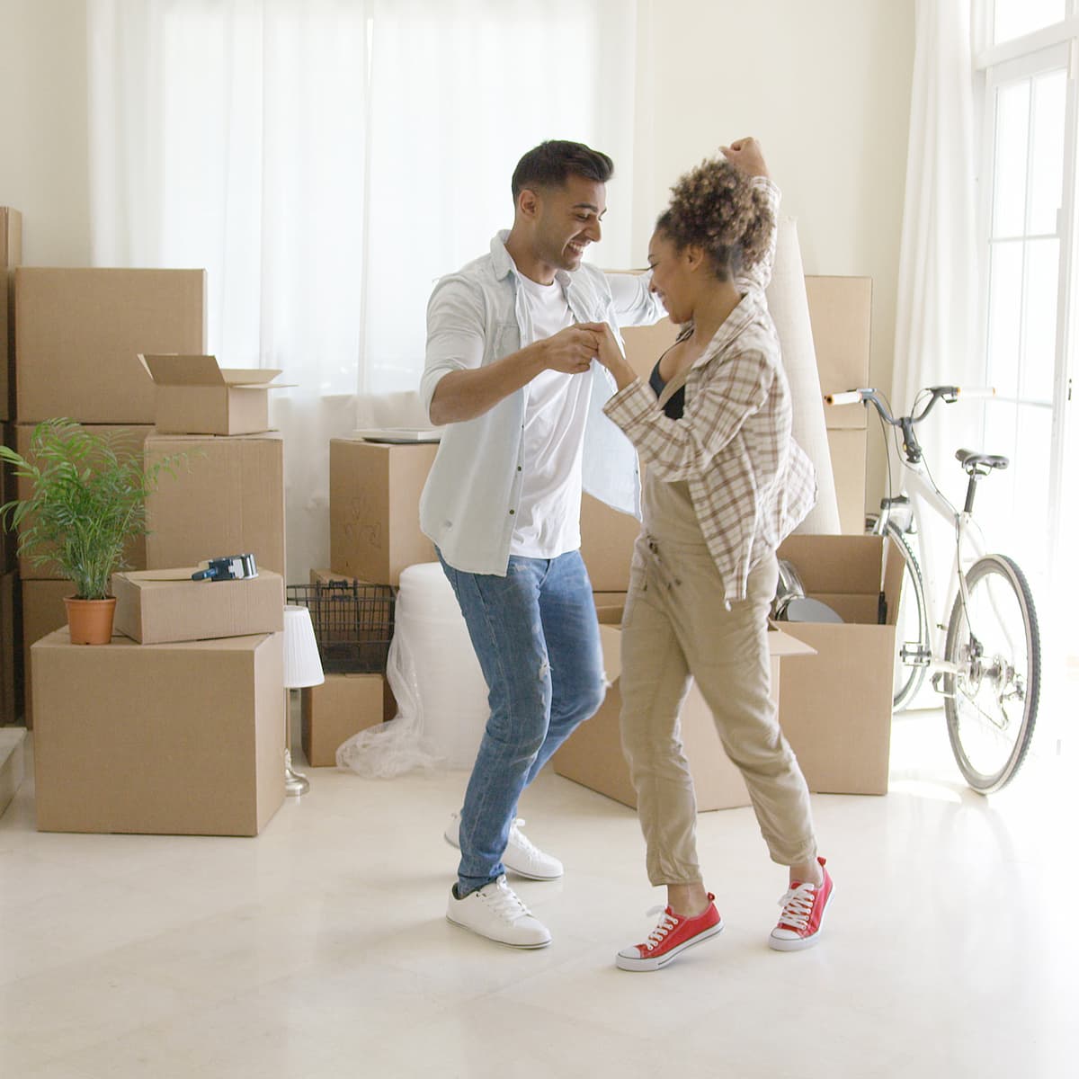 A Young Happy couple dance in the middle of their cozy apartment.