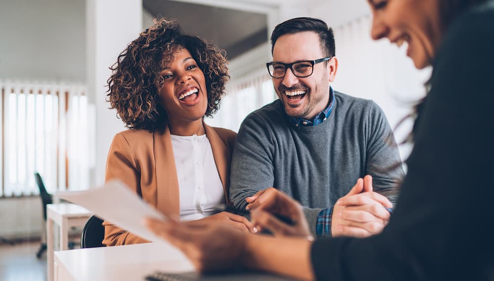 A smiling Man and Woman receiving good news at the from the Mortgage Broker